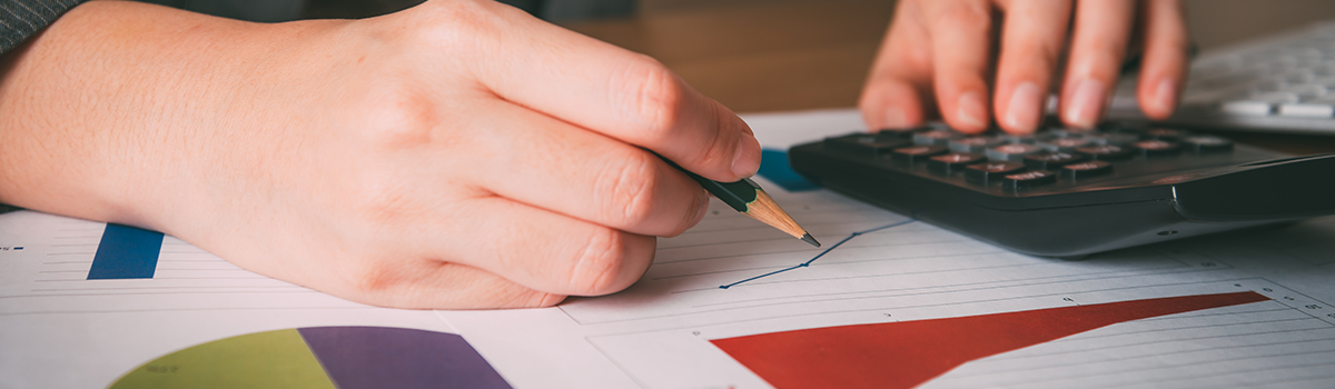 Close up of hands using a calculator and drawing a graph.