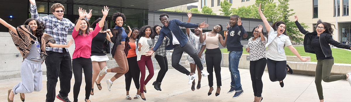 Landscape image of group of people jumping up outdoors.