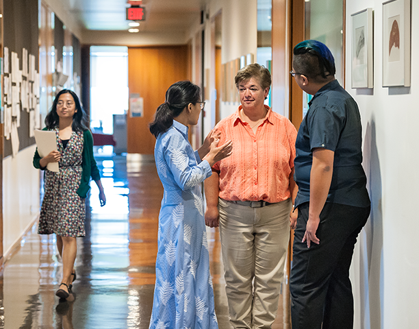 U of T staff talking in one of the campus building hallways.