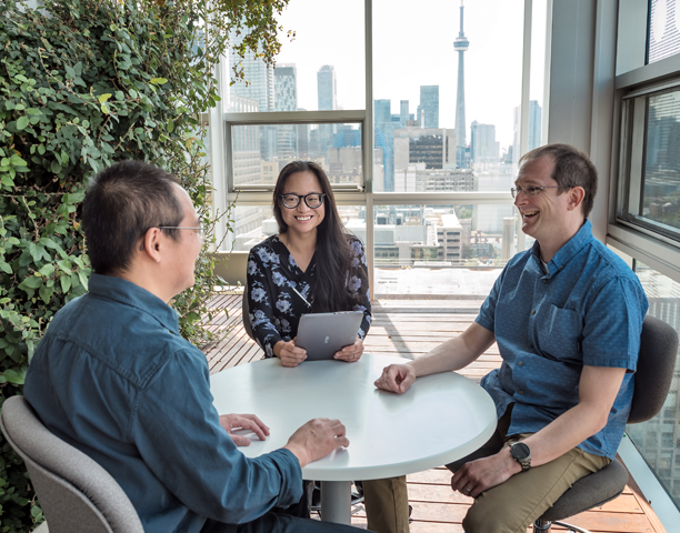 Three staff members sitting at a table talking