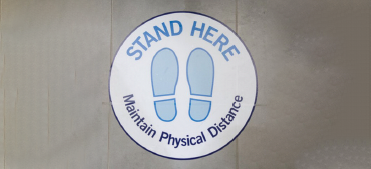 Sticker on the floor: Stand here. Maintain physical distance.
