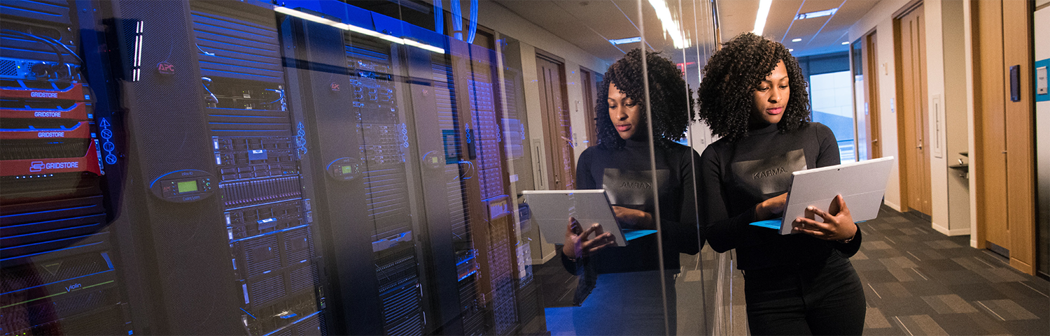 Person using a laptop computer next to the server room.