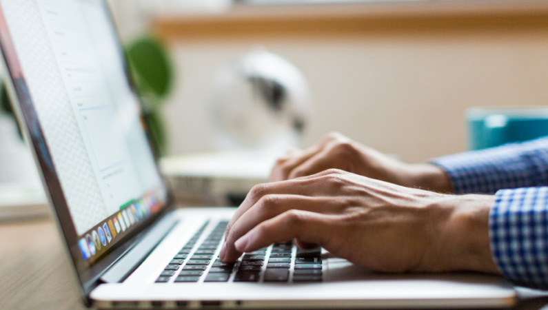 Hands typing on laptop