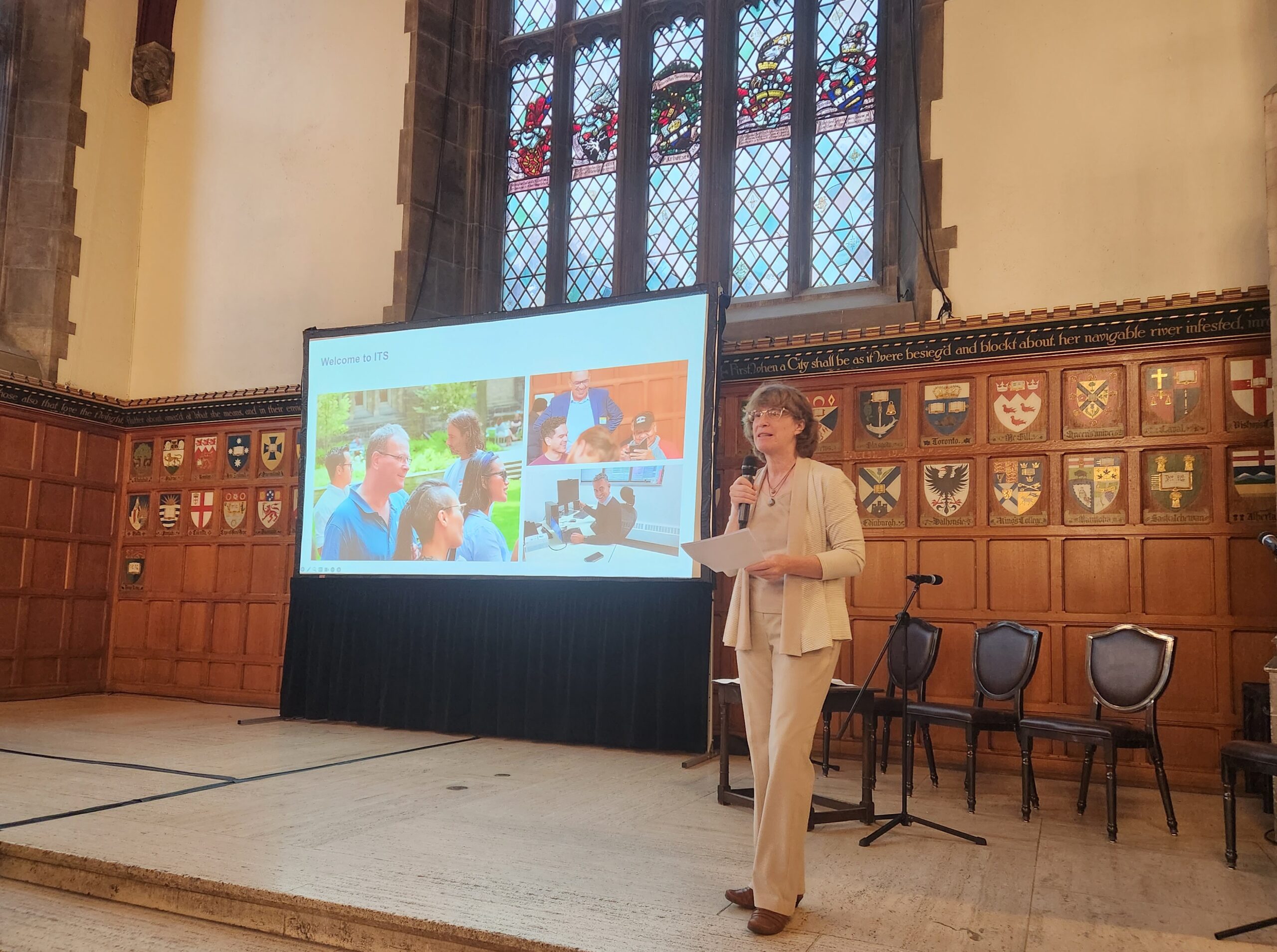 Laurie Harrison speaking into a microphone on stage at the ITS Town Hall