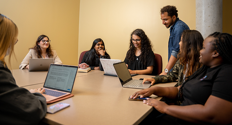 People collaborating in a meeting while using their laptops