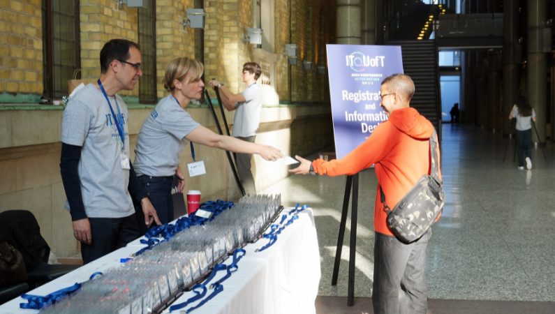 A volunteer handing a name badge to a conference attendee at the registration desk